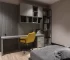 Modern çalışma alanı tasarımı; gri tonlarda modüler duvar ünitesi, sarı ofis sandalyesi ve minimalist dekor.